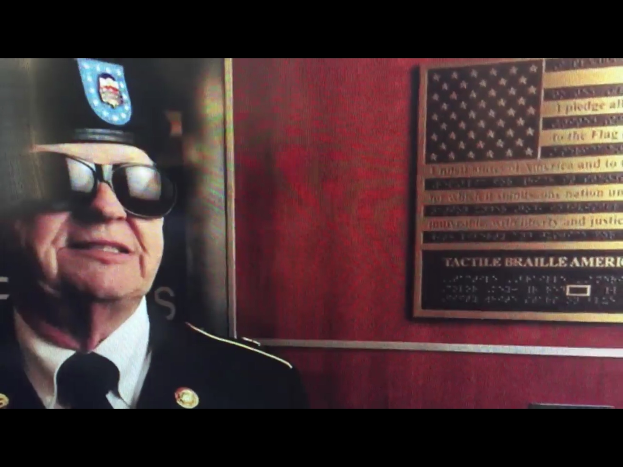 Walt Peters next to Bronze Braille flag